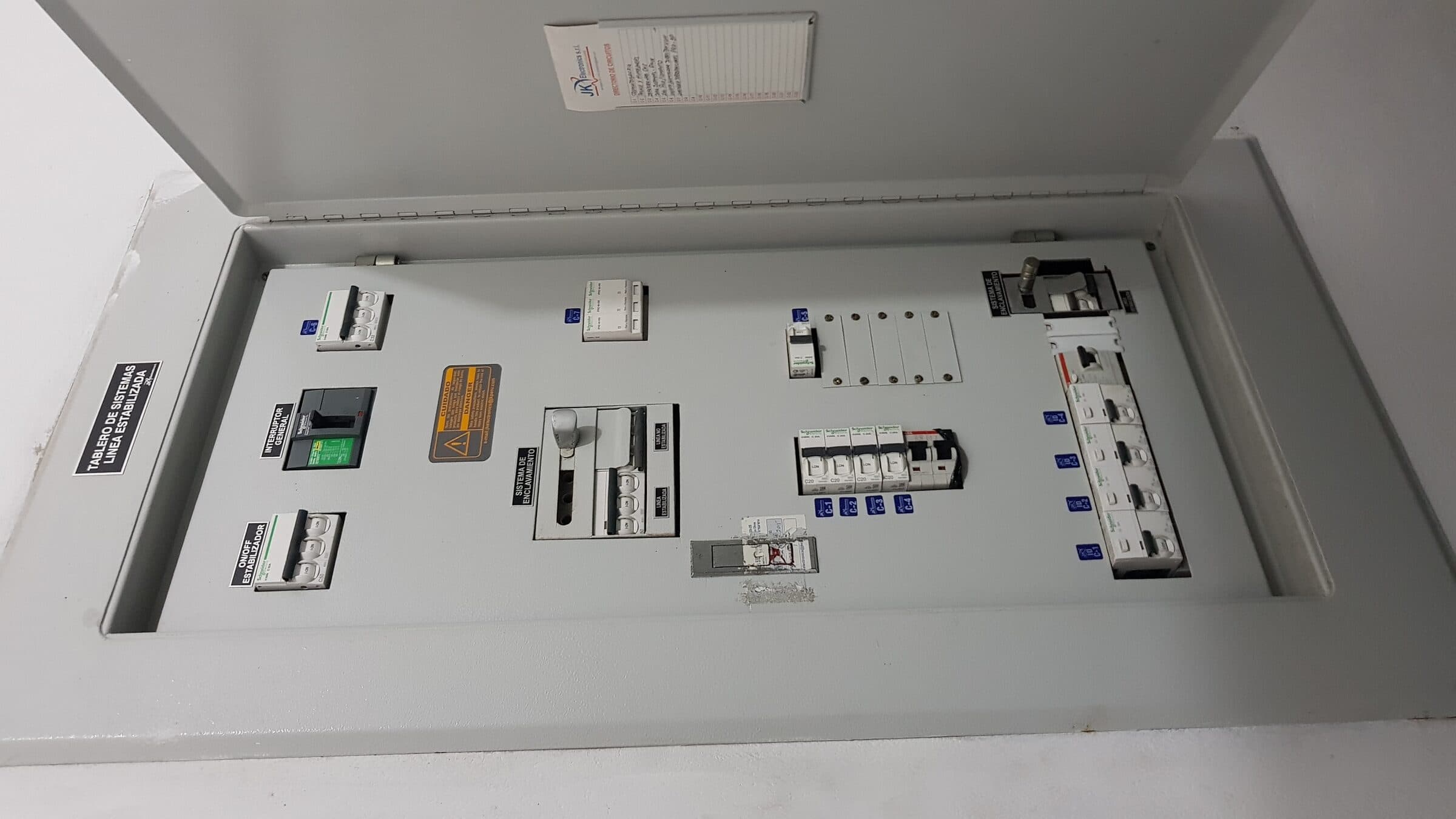 Tablero con la rotulación «Tablero de sistemas línea estabilizada», interruptor general, sistema de enclavamiento y directorio de circuitos de JK Electronics en la puerta