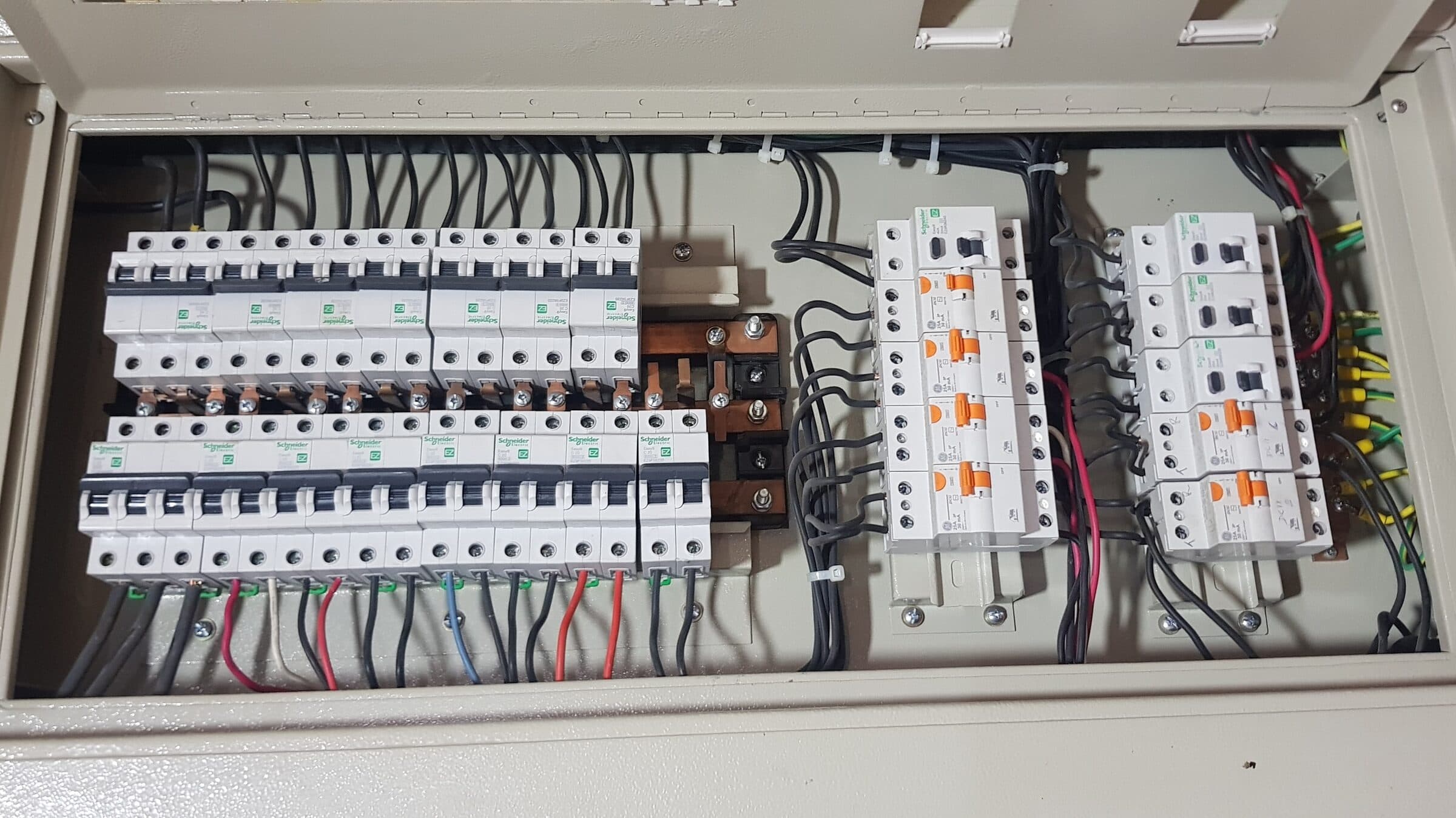 Tablero de distribución abierto con filas de interruptores termomagnéticos, barra de cobre y cableado ordenado